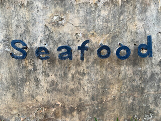 a seafood restaurant outside in tropical country. symbol inscription sea food on stone