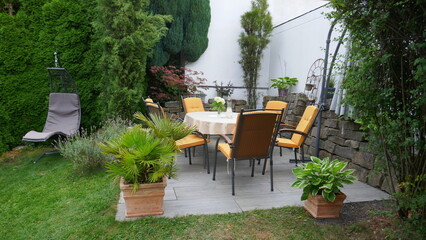 Gartenterrasse mit Sitzgruppe und Hängeschaukel in einer Gartenecke mit Säulen-Faulbaum,...