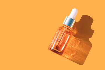 Natural face beauty oil with vitamin C. Dropper bottle with face serum over orange background with shadows and copy space, beauty skin-care products with natural ingredients and fruit essence. Mockup