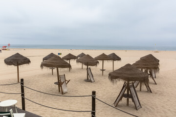 Panoramic general view of the sand of Torreira beach, empty beach, with tourist straw hats, atlantic ocean in the background