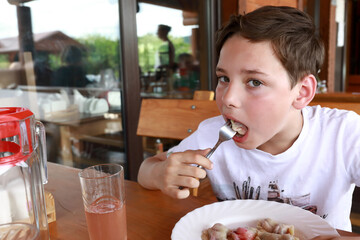 Child eating vareniki stuffed with cherries