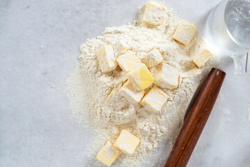 cubes cold butter on all-purpose flour with a jar of ice water in preparation to make puff pastry, basic puff pastry ingredients.