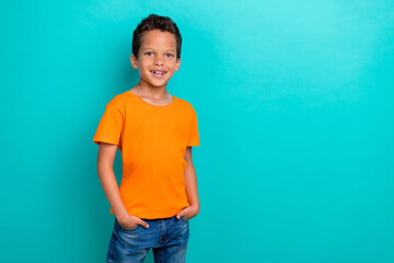 Photo of pretty charming small man wear yellow t-shirt arms pockets empty space isolated turquoise...