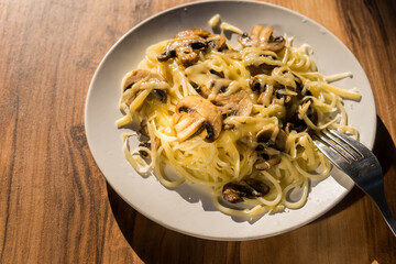 Homemade Italian fettuccine pasta with mushrooms and cream sauce on a dark table