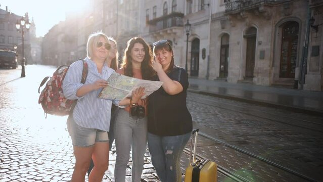 A female tour guide describes the tour and shows tourists a city map during a hot summer day. Tourists with a map in an old city. Go Everywhere