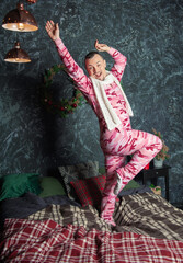 Cheerful funny happy man in sleepwear dancing on bed in Christmas time