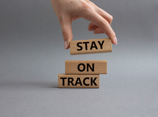 Stay on track symbol. Wooden blocks with words Stay on track. Beautiful grey background. Businessman hand. Business and Stay on track concept. Copy space
