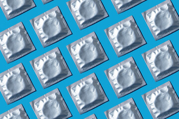 Seamless pattern of condoms in foil packaging on a blue background. Safe sex and reproductive health concept.