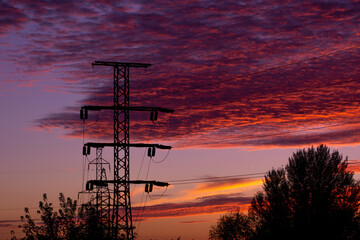 high-voltage tower against the backdrop of a crimson sunset