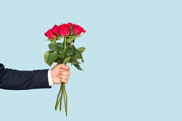 A man's hand holds out a bouquet of roses on a blue background