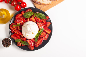 Traditional Italian burrata cheese with salad of delicious cherry tomato, basil leaves and olive oil.
