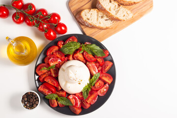 Traditional Italian burrata cheese with salad of delicious cherry tomato, basil leaves and olive oil.