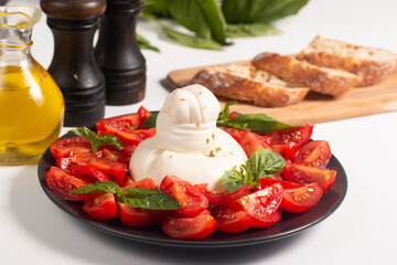 Traditional Italian burrata cheese with salad of delicious cherry tomato, basil leaves and olive oil.