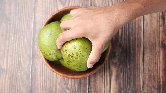 hand pick Fresh green mango in a bowl on table 