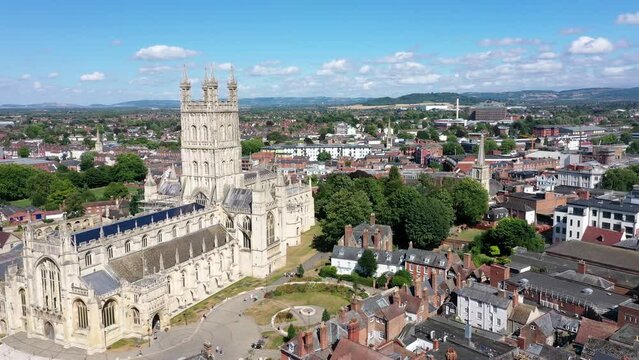 Aerial side pass footage of Gloucester Cathedral on a sunny day.