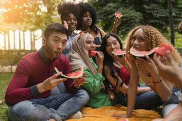 multiracial friends eating watermelon in the park