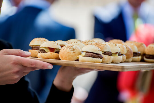 Camarero con bandeja de mini hamburguesas