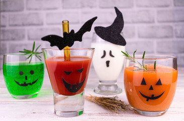Different drinks for Halloween in glasses decorated with scary faces.
