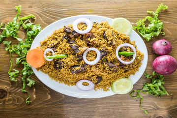Akhni Biriyani with onion, pepper and salad served in a dish isolated on wooden table top view of indian and bangladesh food
