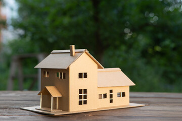 Real estate concept. House of dreams - Invest in a family home. Modern house model in a garden.
