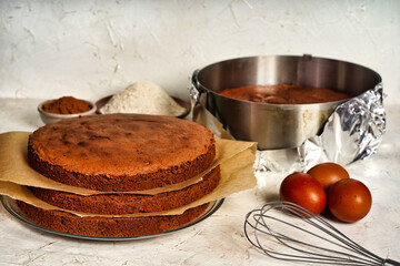 Chocolate sponge flourless cake layers with bake paper, light background. Brownie cake