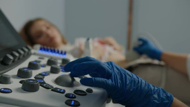 Close-up of the doctor's hand on the ultrasound machine during the examination of the patient