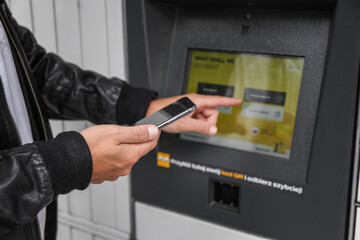 Warszaw, Poland - August, 2022:an with a smartphone in his hands near the self-service mail...