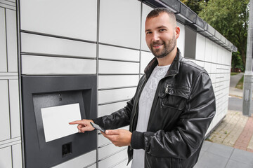man with a smartphone in his hands near the self-service mail terminal. Parcel delivery machine.