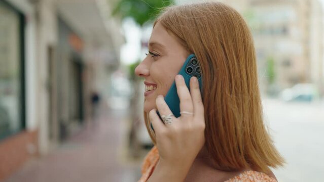 Young redhead woman smiling confident talking on the smartphone at street