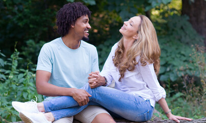 Young mixed race couple talking while sitting in the summer nature