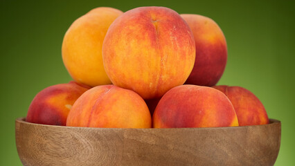 Peaches. Fresh peaches in wooden bowl. Juice peach fruits on green background