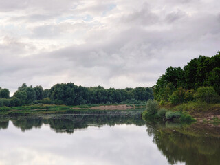Forest river view summer landscape. Beautiful wild nature scene with water and oak trees on the shore. Klyazma, Vladimir Oblast, Russia. Cloudy weather, rain clouds