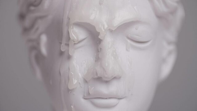 drops of wax fall on the head of an antique statue close-up