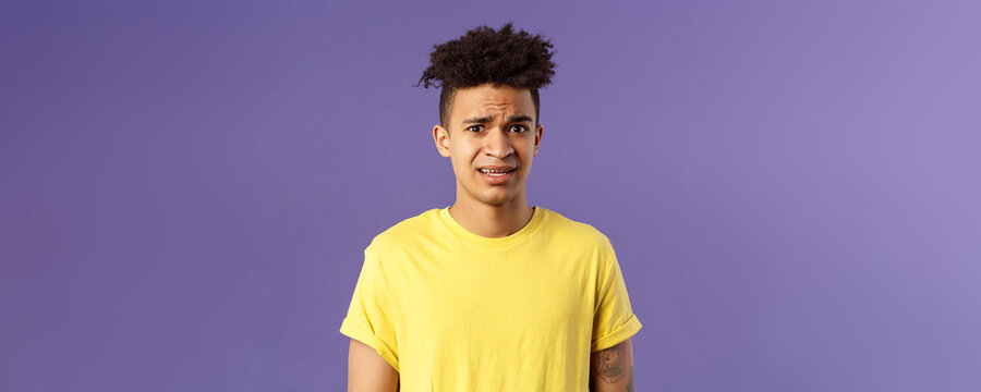 Close-up Portrait Of Awkward And Embarrassed Young Hispanic Guy Looking Nervous, Meeting Girlfriend Parents, Stare Scared And With Panic, Feeling Concerned, Cringe Over Purple Background