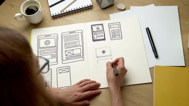 UI designer sketches the user interface of a web application for a mobile phone. A developer creates a prototype for a smartphone.