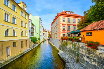 Fototapeta na wymiar Colorful cafes, homes and buildings along the Certovka Canal as it crosses under Charles Bridge in the Old Town Lesser Quarter area of Prague, Czechia.
