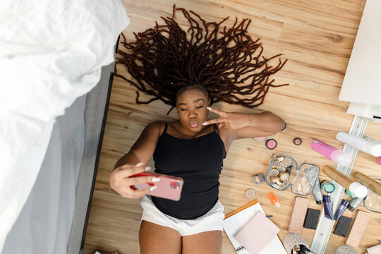 View from above woman with long dreadlocks taking selfie, gesturing