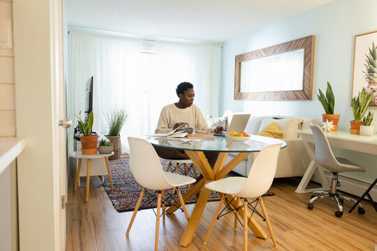 Woman Working From Home And Eating At Kitchen Table