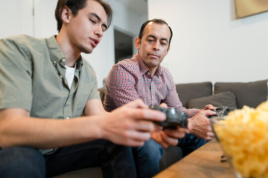 Son Teaching Father How To Play Video Game In Living Room