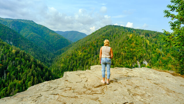 A woman observes the beautiful nature. A view of the most beautiful mountains in a panoramic scene. View from Tomasovsky Vyhlad in Slovak Paradise National Park. Blue haze in the air.