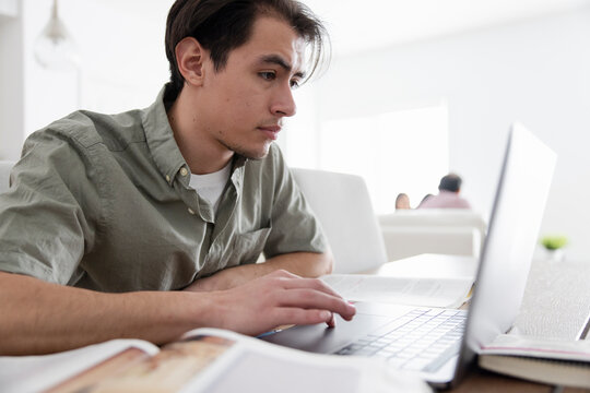 Focused Male College Student Studying At Laptop At Home