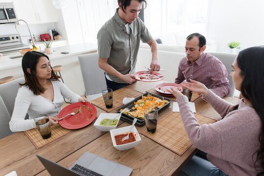 Family eating homemade nachos at dining table