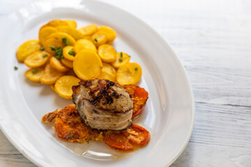 pork tenderloin in bacon on pepper with potatoes and tomatoes