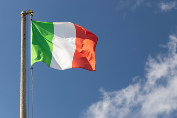 Italian flag blowing in the wind in the blue sky