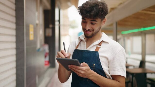 Young arab man waiter using touchpad working at restaurant