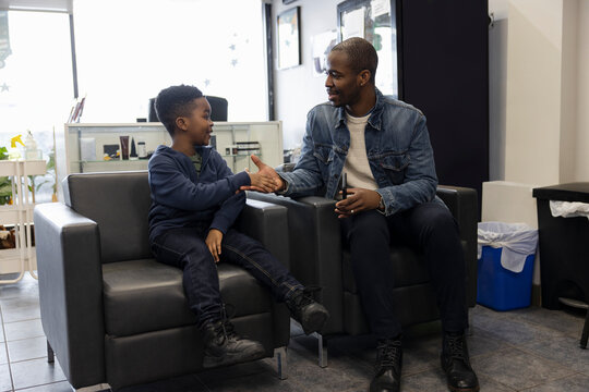 Father and son customers shaking hands, waiting in barber shop