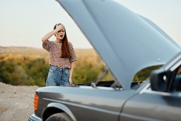 Woman sad and angry about car breakdown on road trip alone and putting her hands on her head from not understanding, car problem