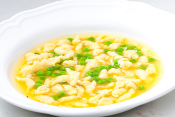 chicken bouillon with homemade dumplings and green peas