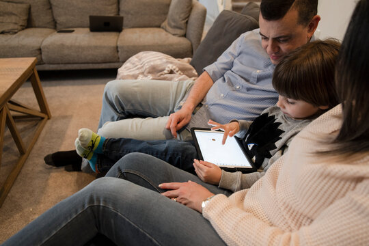 Family drawing on digital tablet screen on living room sofa