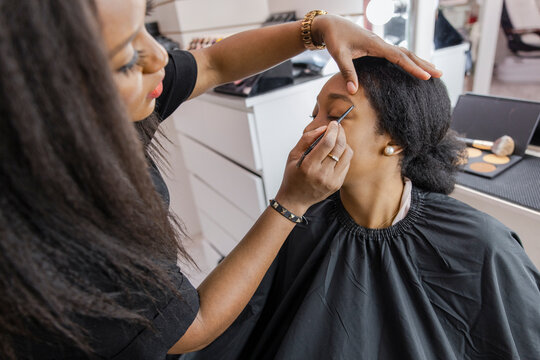Makeup artist applying brow pencil to customer in beauty salon